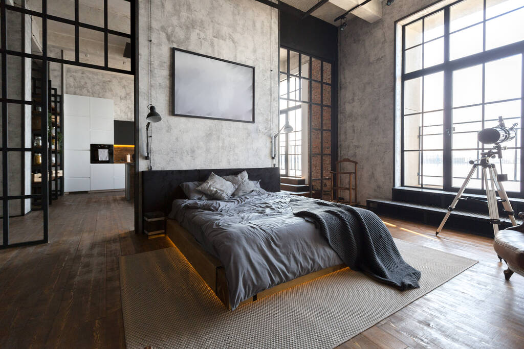 luxury studio apartment with a free layout in a loft style in dark colors. Stylish modern kitchen area with an island, cozy bedroom area with fireplace and personal gym - Photo, Image