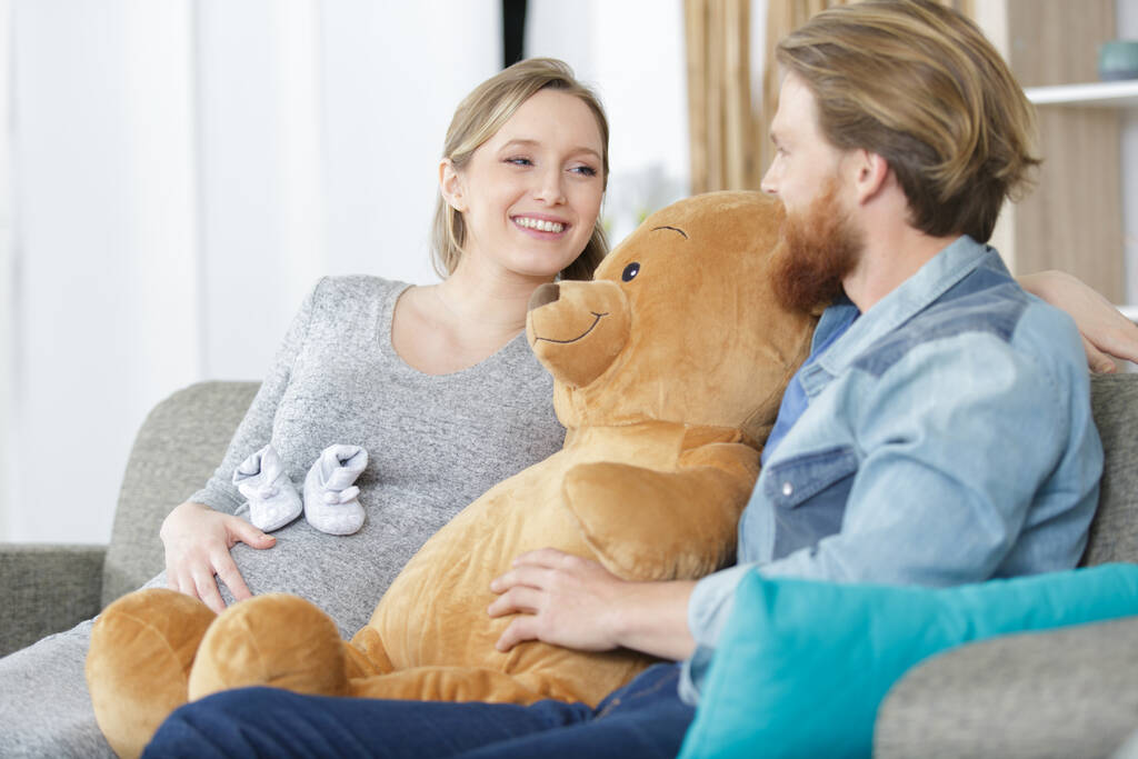 smiling pregnant woman and husband with a teddy bear - Photo, Image