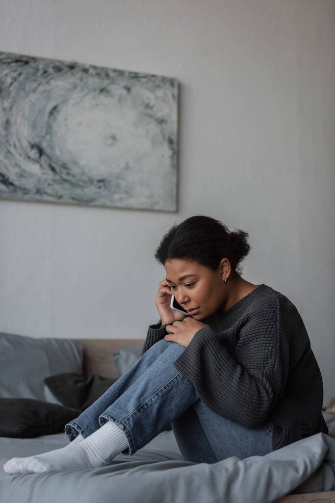 Frustrierte multirassische Frau ruft in der Hotline an, während sie zu Hause auf dem Bett sitzt  - Foto, Bild