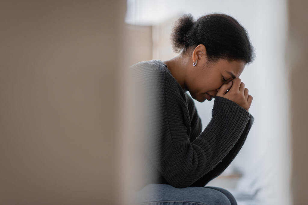 Seitenansicht einer multirassischen Frau mit psychischen Problemen, die zu Hause weint  - Foto, Bild