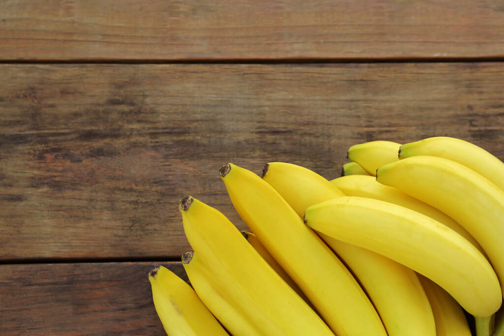 Reife gelbe Bananen auf Holztisch, flach gelegt. Raum für Text - Foto, Bild