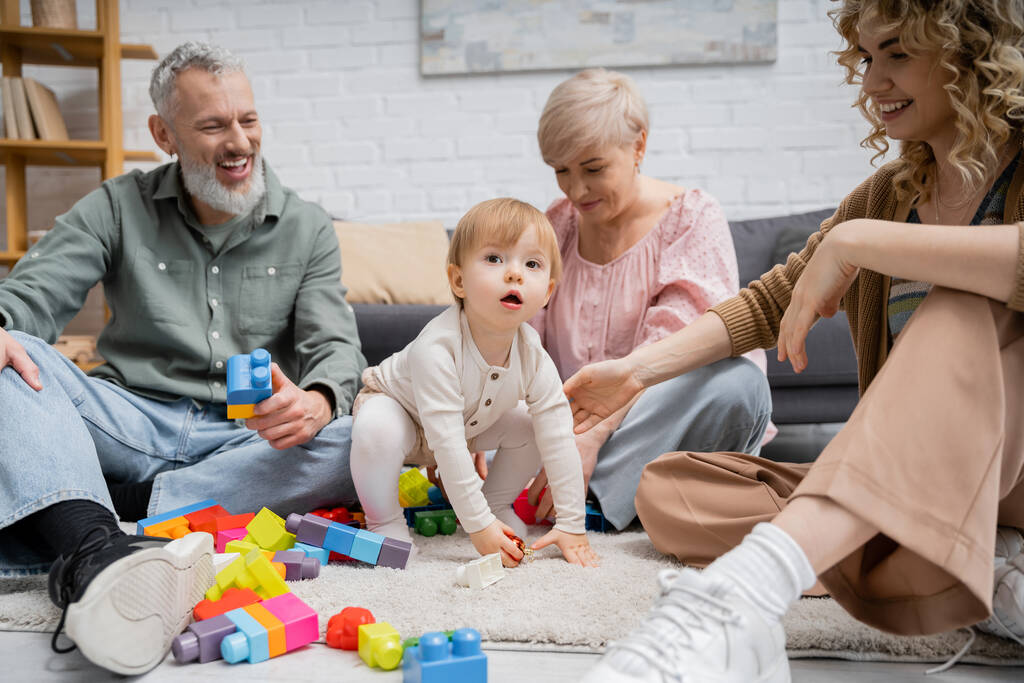 baba lány néz félre játékok és boldog család a padlón a nappaliban - Fotó, kép