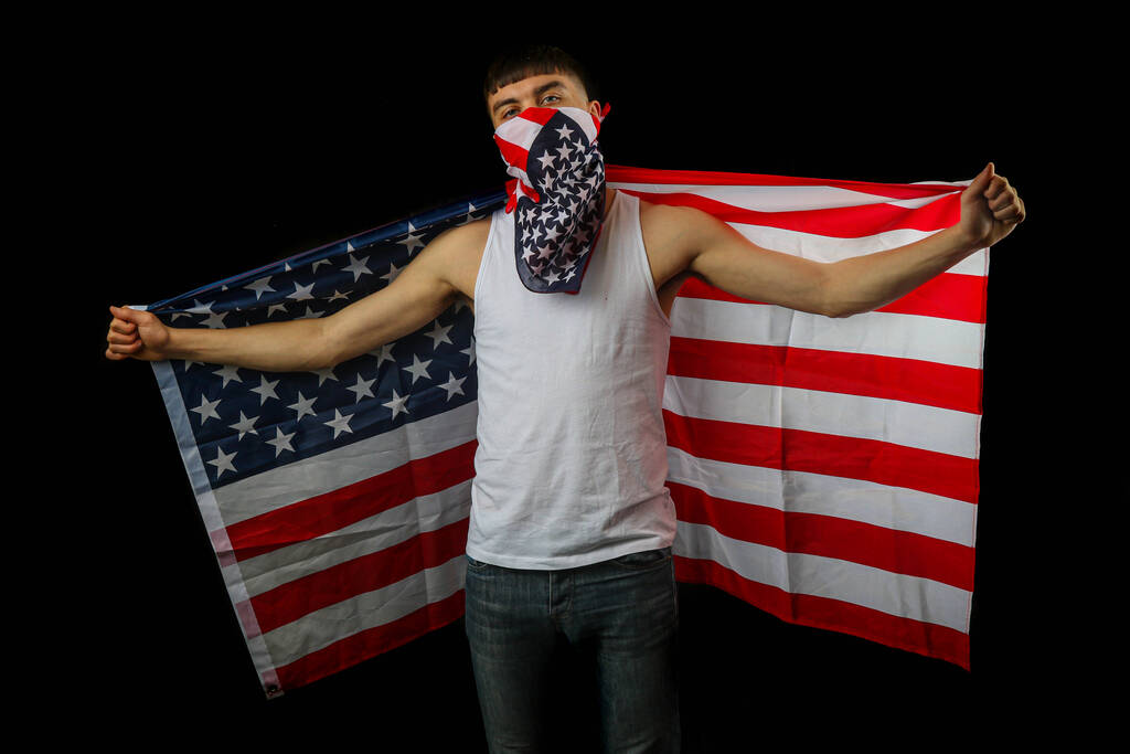 Teini-ikäinen poika valkoisessa liivissä Amerikan lippu naamio ja lippu mustalla taustalla - Valokuva, kuva
