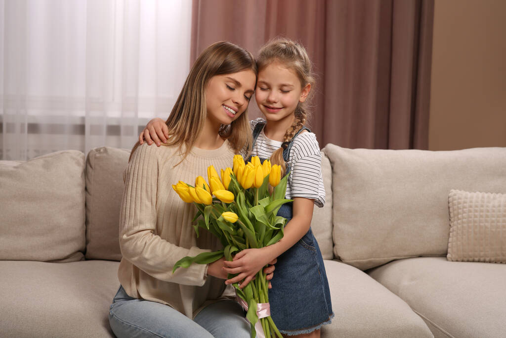 Маленькая дочь поздравляет маму с букетом желтых тюльпанов дома. С Днем матери! - Фото, изображение