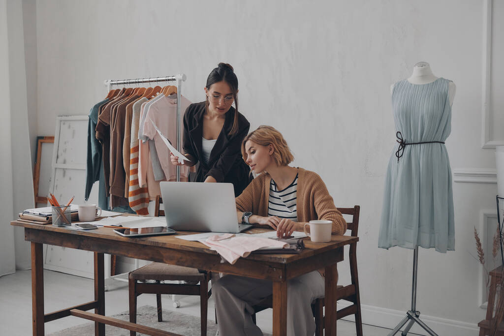 Dos confiadas diseñadoras de moda trabajando en una nueva colección en el taller - Foto, imagen