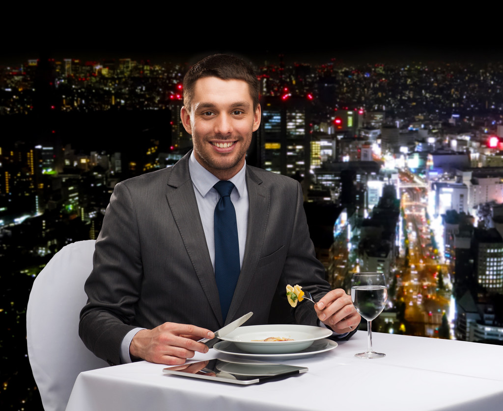 smiling man with tablet pc eating main course - Photo, Image