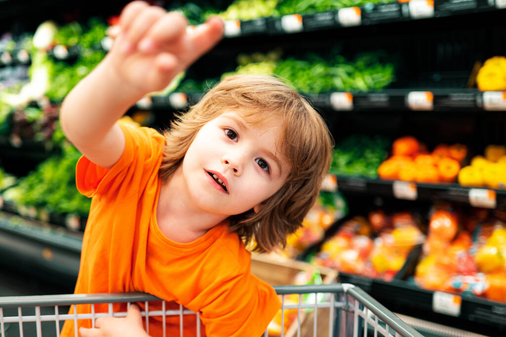Verkoop, consumentisme en mensen concept - kinderen met voedsel in winkelwagen bij de supermarkt - Foto, afbeelding