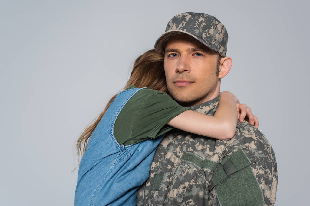 Mädchen umarmt Vater in Militäruniform während Gedenktag isoliert auf grau  - Foto, Bild