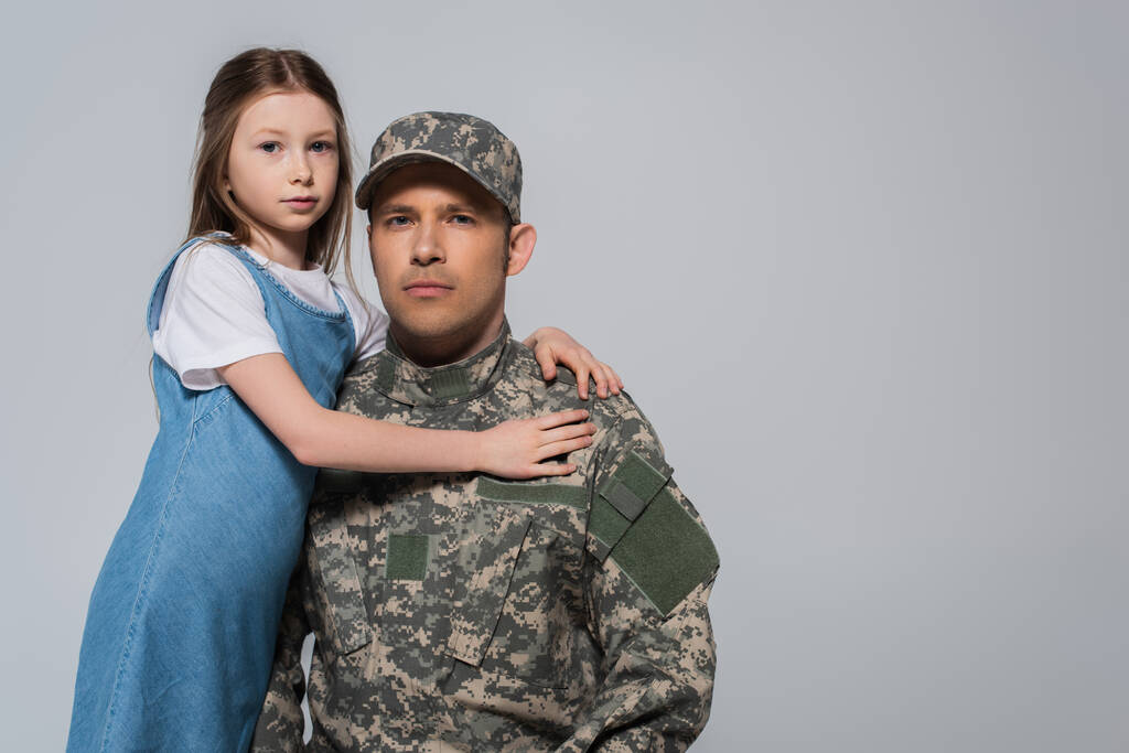Frühchen umarmt Vater in Armeeuniform während Gedenktag isoliert auf grau  - Foto, Bild