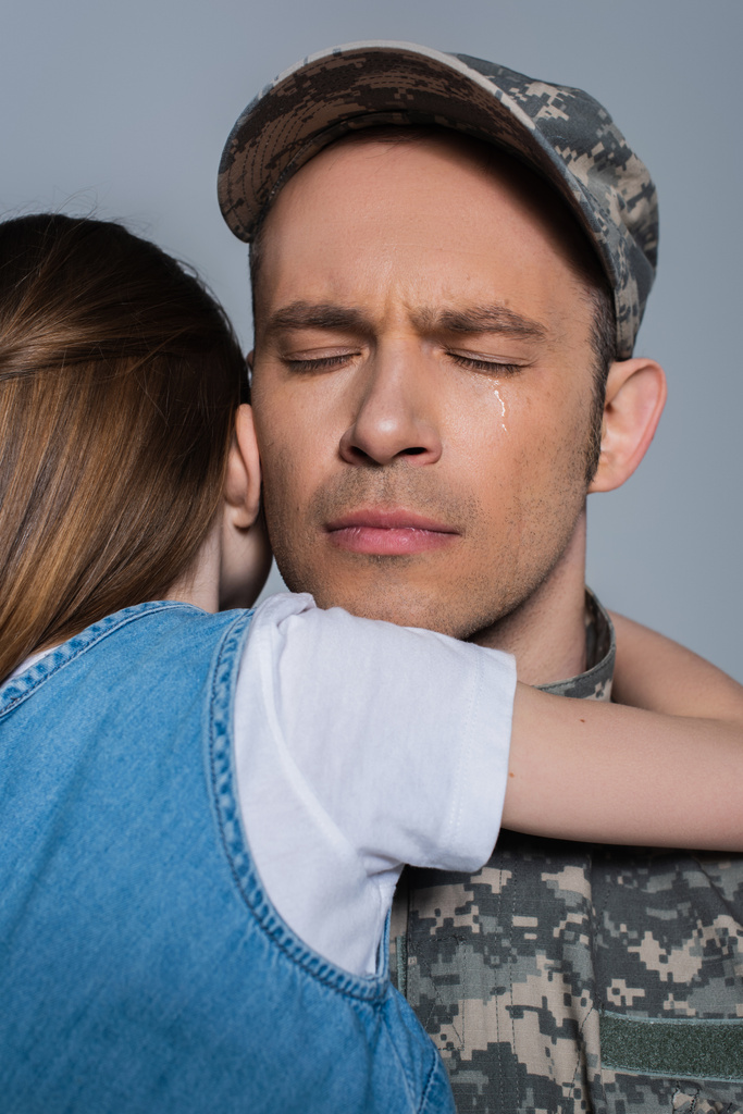 sentimentele militair in militair uniform huilen en knuffelen met dochter tijdens herdenkingsdag geïsoleerd op grijs  - Foto, afbeelding
