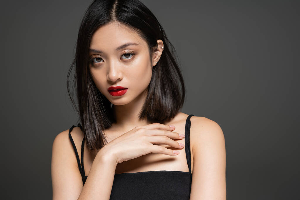 portrait of elegant asian woman with red lips looking at camera isolated on grey - Photo, Image