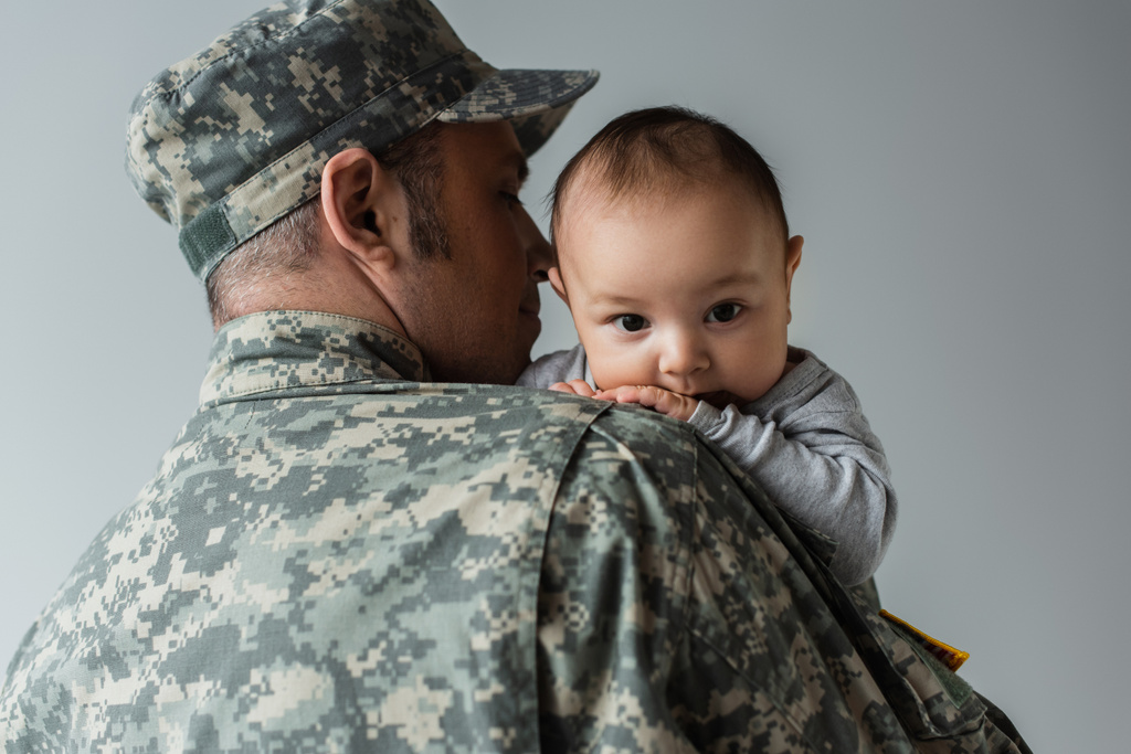ojciec w mundurze wojskowym i czapce przytulając nowonarodzonego chłopca odizolowanego na szaro  - Zdjęcie, obraz