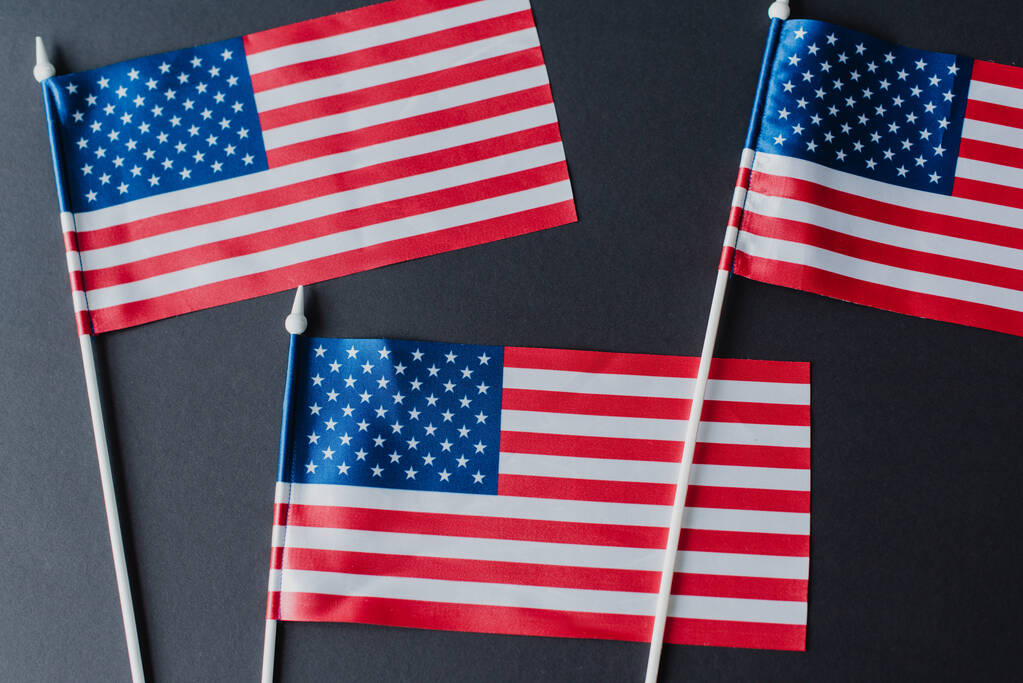 верхний вид трех американских флагов со звездами и полосами, изолированными на черном  - Фото, изображение