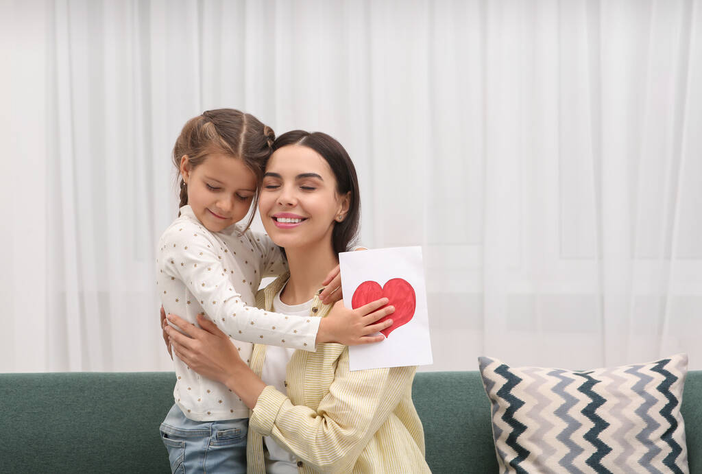 Femme heureuse avec sa fille et carte de vœux faite à la main sur le canapé à la maison, espace pour le texte. Fête des mères - Photo, image