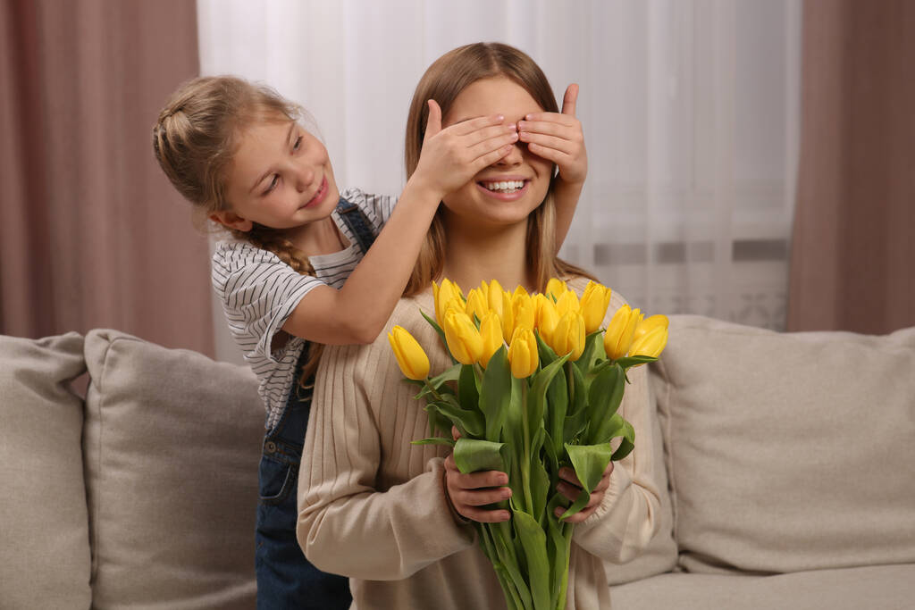 Hijita felicitando a mamá con ramo de tulipanes amarillos en casa. Feliz Día de la Madre - Foto, imagen