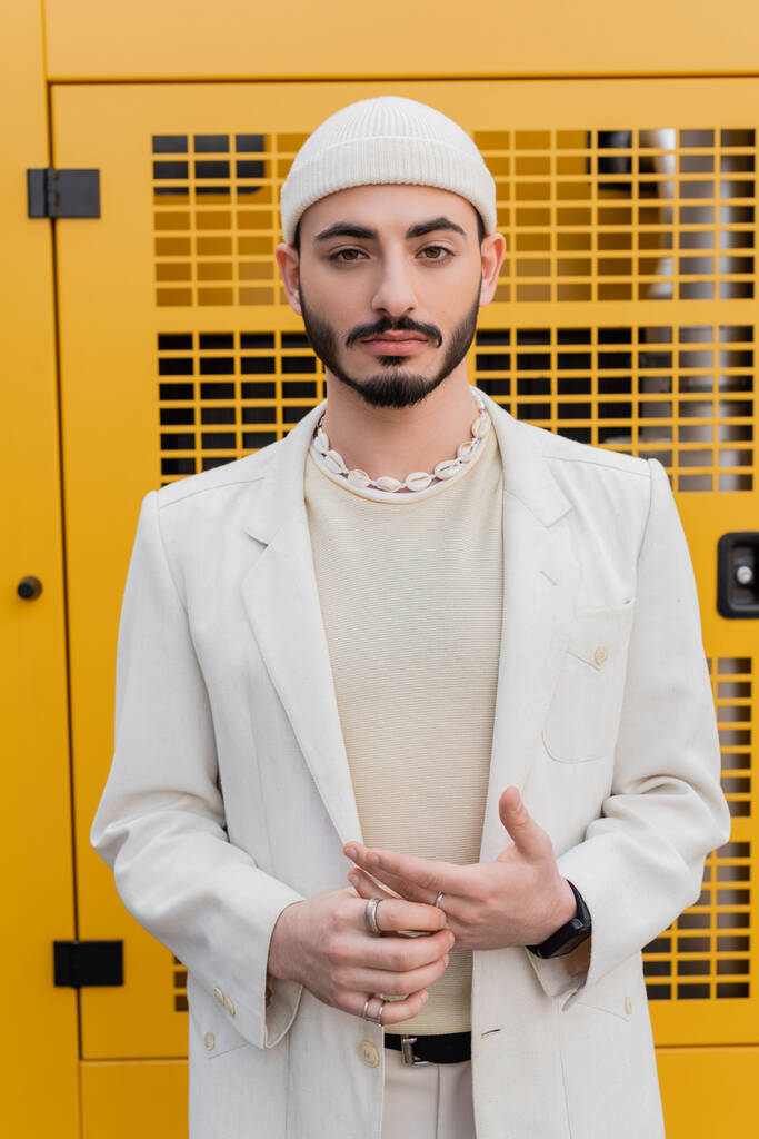 Portrét stylového gaye v klobouku a bundě při pohledu na kameru venku  - Fotografie, Obrázek