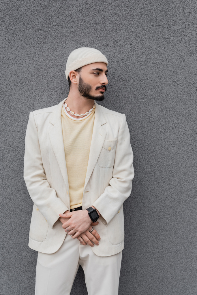 ben vestito gay uomo in beige vestito e cappello in piedi vicino muro all'aperto  - Foto, immagini