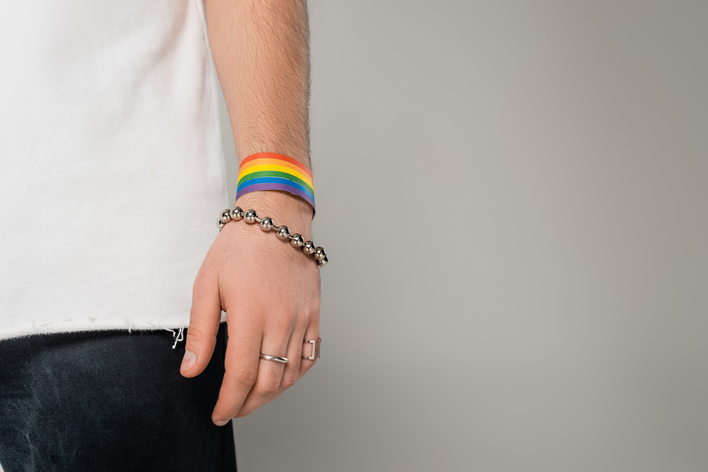 Обрізаний вид гомосексуального чоловіка з браслетом lgbt на руці стоїть ізольовано на сірому
   - Фото, зображення