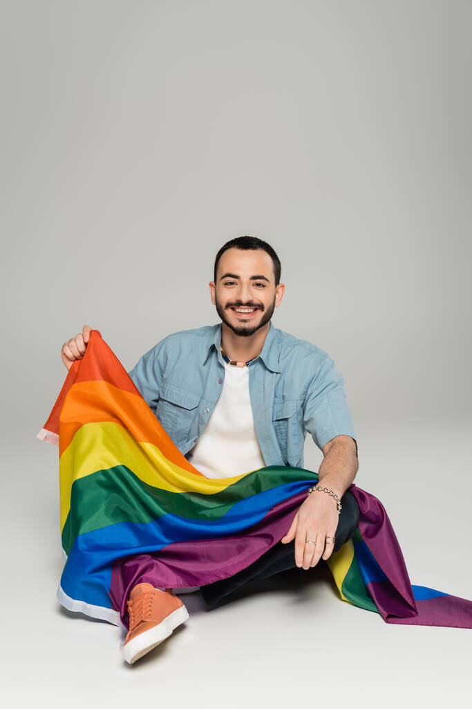positif gay l'homme tenant lgbt drapeau tandis que assis sur gris fond  - Photo, image