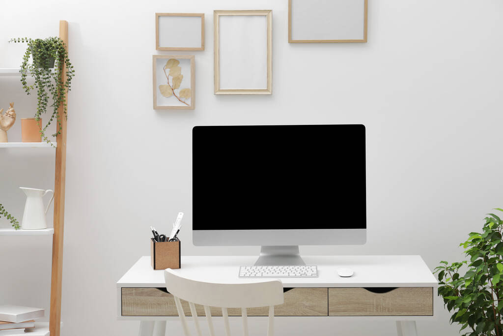 Acogedor espacio de trabajo con escritorio, silla, computadora y plantas en casa - Foto, imagen
