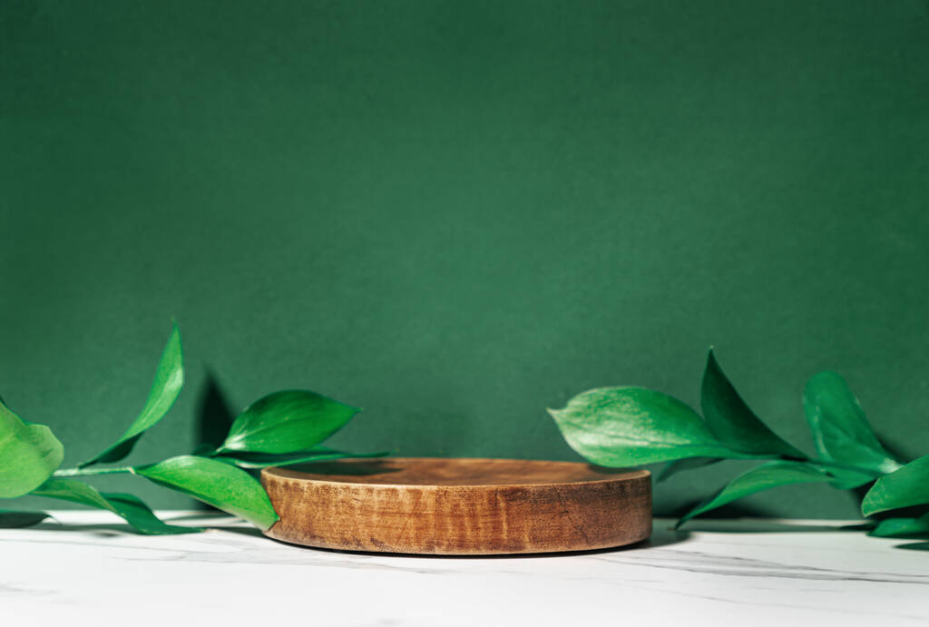Scena di presentazione del prodotto realizzata con piedistallo in legno e foglie verdi, vista frontale. - Foto, immagini