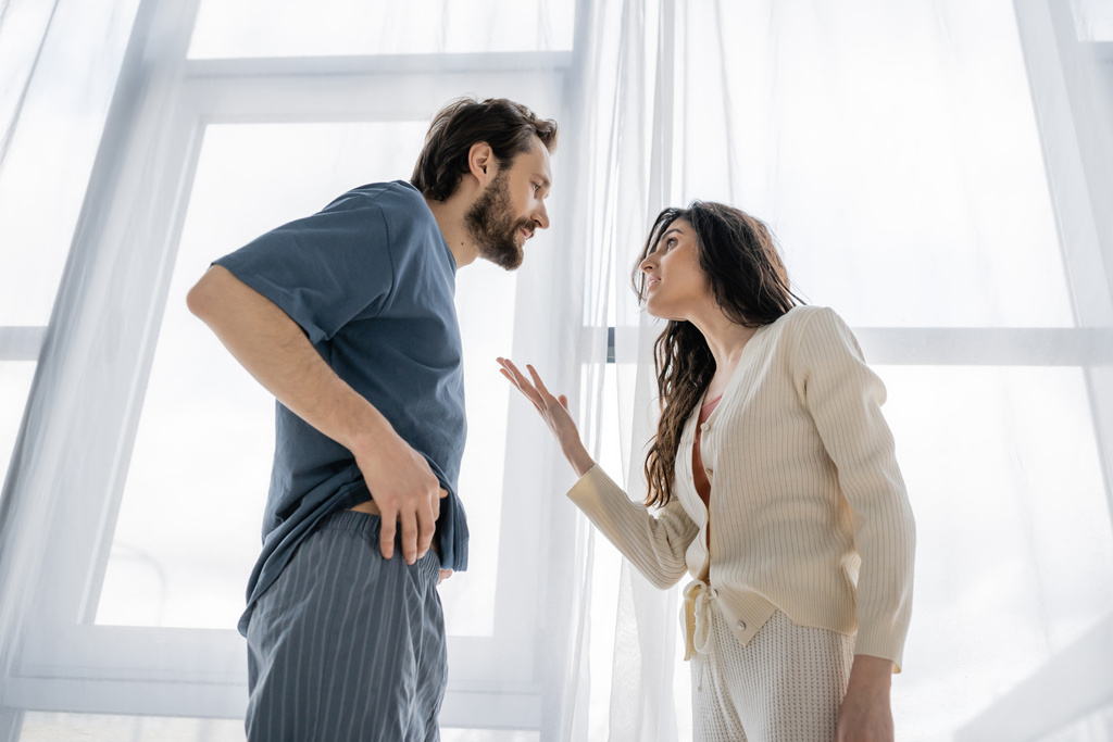Vue à angle bas de la femme agressive parlant à son petit ami pendant le conflit à la maison  - Photo, image