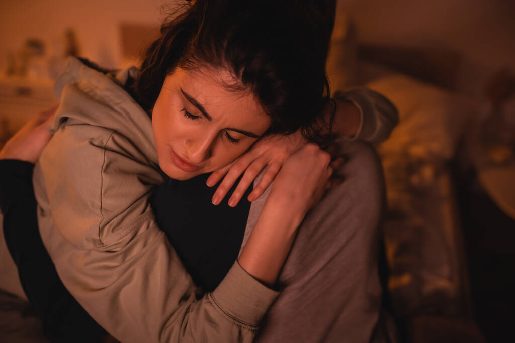 Nespokojená žena objímající přítele v ložnici v noci  - Fotografie, Obrázek