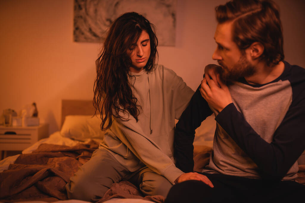 Bruna donna calmante fidanzato sul letto in serata  - Foto, immagini