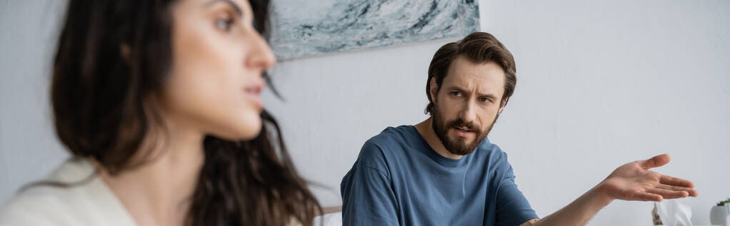 Ображений чоловік, який вказує рукою, розмовляючи з розмитою дівчиною вдома, банер
  - Фото, зображення