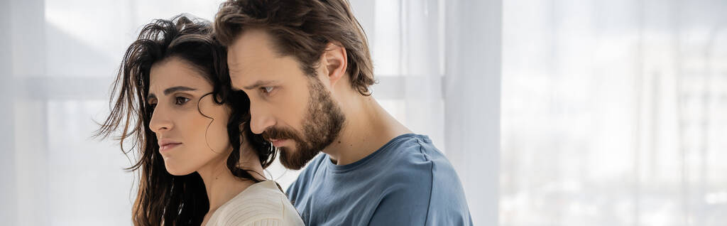 Бородатый мужчина смотрит на расстроенную девушку брюнетку дома, баннер  - Фото, изображение