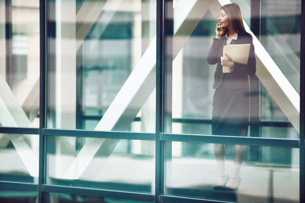 Contacte a un cliente influyente. una mujer de negocios usando un teléfono móvil en una moderna oficina de vidrio - Foto, imagen