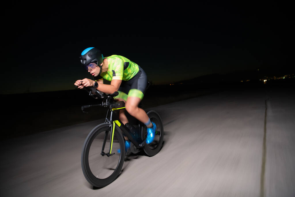 Триатлоніст їде на велосипеді в темряві ночі, штовхаючи себе готуватися до марафону. Контраст між темрявою і світлом велосипеда створює відчуття драми і підкреслює
 - Фото, зображення