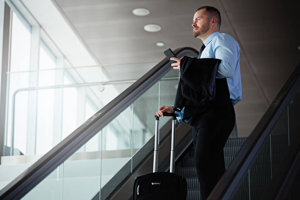 Ekspert od podróży służbowych. biznesmen podróżujący schodami ruchomymi na lotnisku - Zdjęcie, obraz