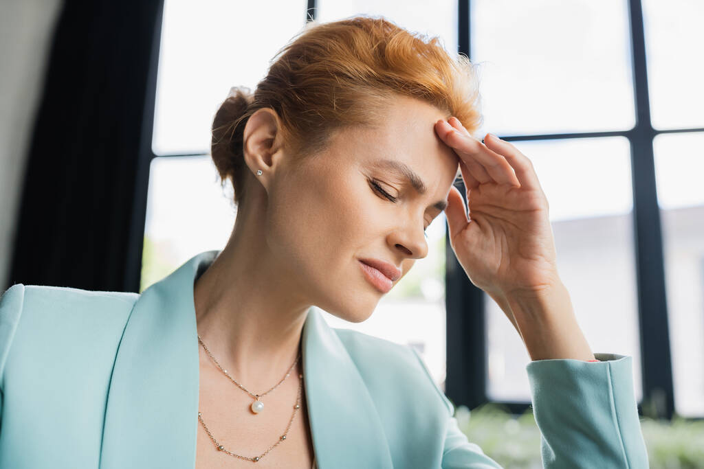 オフィスで片頭痛に苦しみながら目を閉じて額に触れるビジネス女性を眉をひそめる - 写真・画像