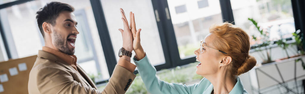 opgetogen zakenpartners kijken elkaar aan en geven high five in office, banner - Foto, afbeelding