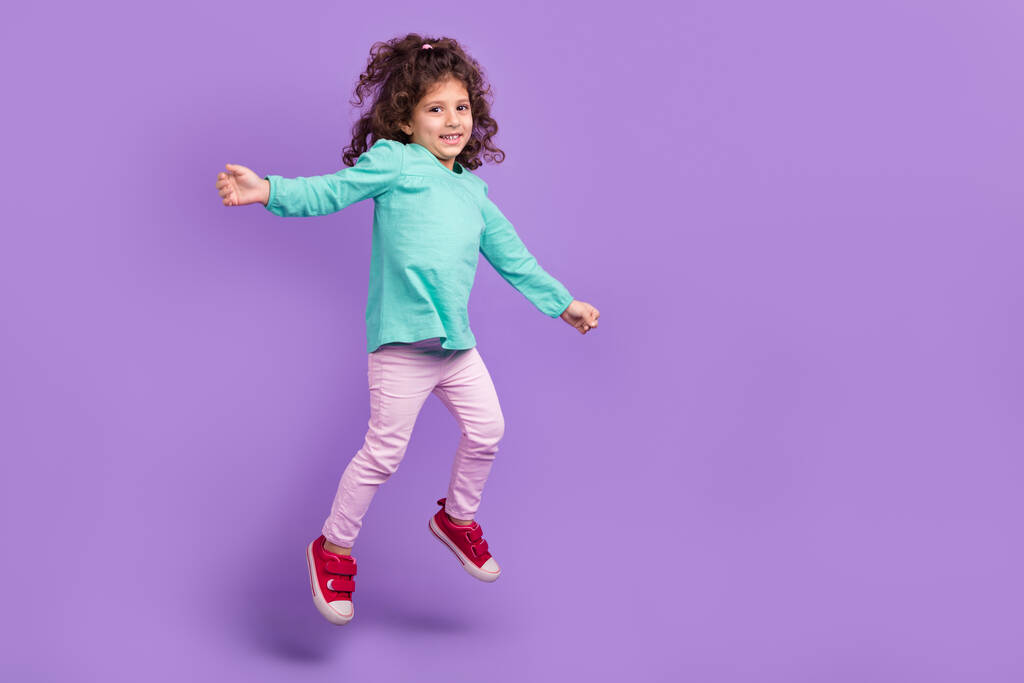Πλήρης φωτογραφία του χαριτωμένα αξιολάτρευτο μικρό παιδί φορούν τιρκουάζ πουκάμισο άλμα υψηλό κενό χώρο απομονωμένο βιολετί φόντο χρώμα. - Φωτογραφία, εικόνα