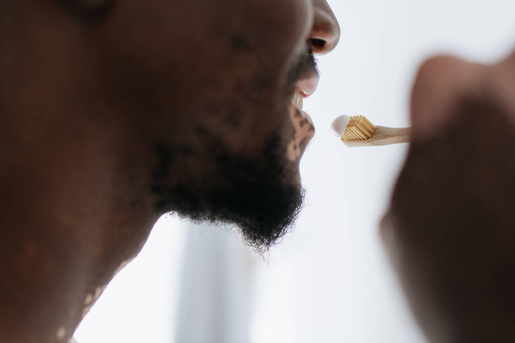 Περικοπή άποψη της Αφρικής Αμερικανός άνθρωπος με λεύκη βούρτσισμα των δοντιών στο σπίτι  - Φωτογραφία, εικόνα