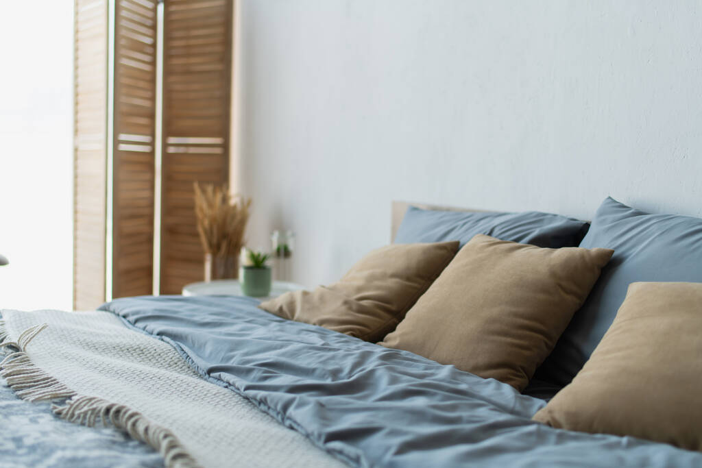 Μαξιλάρια σε άνετο κρεβάτι σε θολή κρεβατοκάμαρα  - Φωτογραφία, εικόνα