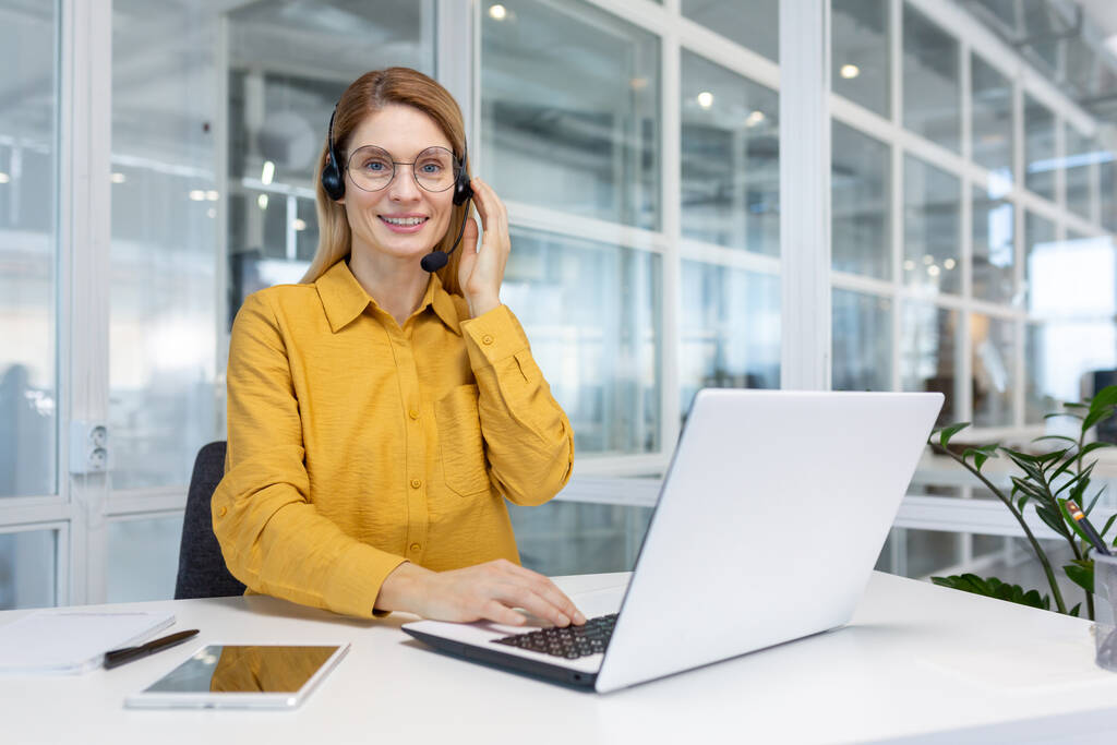 Portret bizneswoman, pracownik biurowy patrząc w aparat fotograficzny i uśmiechnięty, za pomocą słuchawki i laptopa do zdalnej komunikacji online, obsługa klienta tech call center pracownik - Zdjęcie, obraz