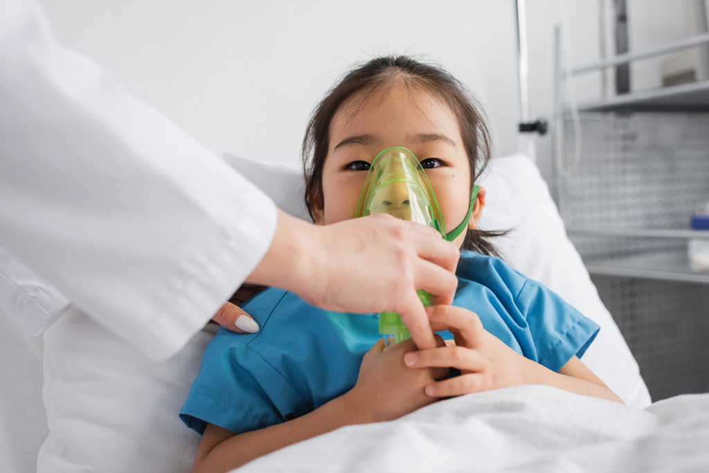 Μια Ασιάτισσα που αναπνέει μάσκα οξυγόνου κοντά σε γιατρό στο νοσοκομείο. - Φωτογραφία, εικόνα