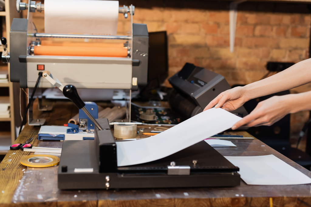 περικοπή άποψη της γυναίκας κρατώντας χαρτί κοντά στο ψαλίδι χαρτί στο κέντρο εκτύπωσης  - Φωτογραφία, εικόνα