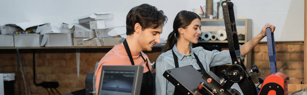 χαρούμενα τυπογράφοι σε ποδιές χρησιμοποιώντας επαγγελματικό plotter εκτύπωσης, ενώ εργάζονται μαζί στο κέντρο εκτύπωσης, banner  - Φωτογραφία, εικόνα