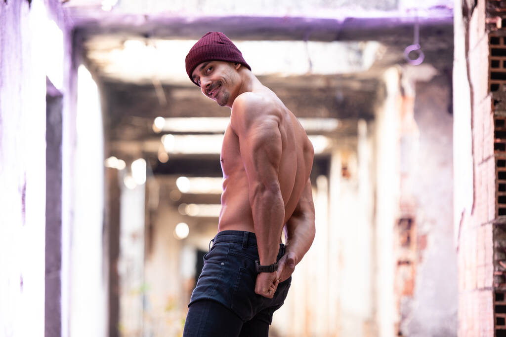 Υγιής νεαρός άνδρας στέκεται ισχυρή κάμψη των μυών στα ερείπια - Muscular Athletic Bodybuilder Fitness Model Posing Outdoors - Φωτογραφία, εικόνα