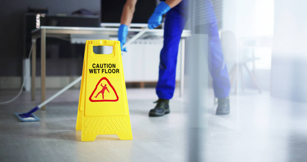 Section basse de plancher de nettoyage de concierge masculin avec la prudence Wet Floor Sign In Office
 - Photo, image
