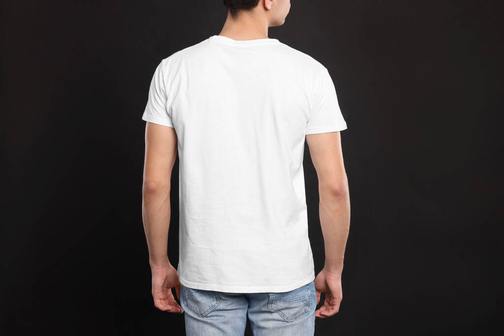 Hombre vistiendo camiseta blanca sobre fondo negro, vista trasera. Burla para el diseño - Foto, Imagen