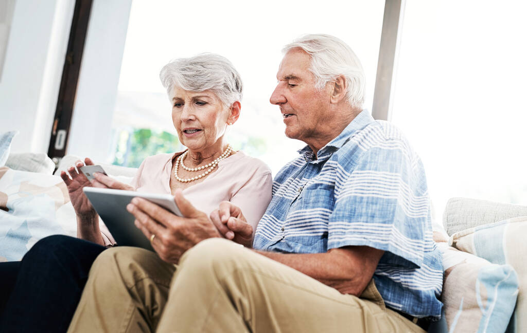 Magába foglalja a technológia és a hitel kényelmét. egy idős pár, akik otthon digitális táblagépen hajtanak végre hitelkártya-fizetést - Fotó, kép
