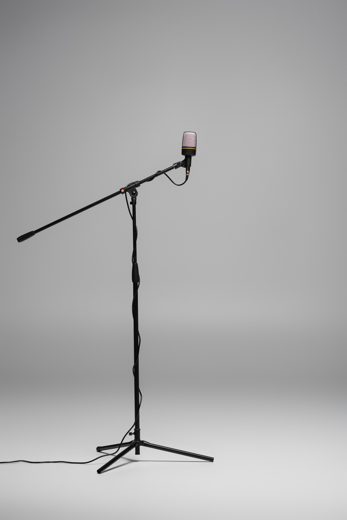 Czarny mikrofon z drutem na stojaku na szarym tle z przestrzenią do kopiowania, studio shot  - Zdjęcie, obraz