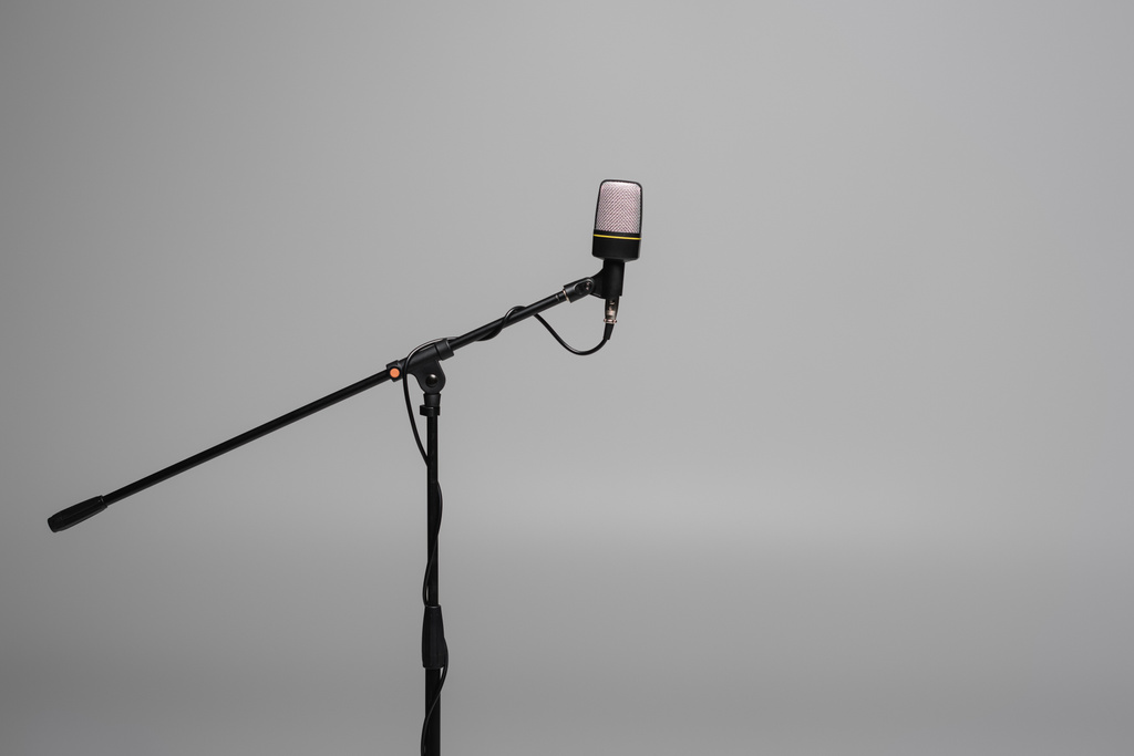 Schwarzes Mikrofon mit Draht auf Metallständer isoliert auf grau mit Kopierraum, Studioaufnahme  - Foto, Bild