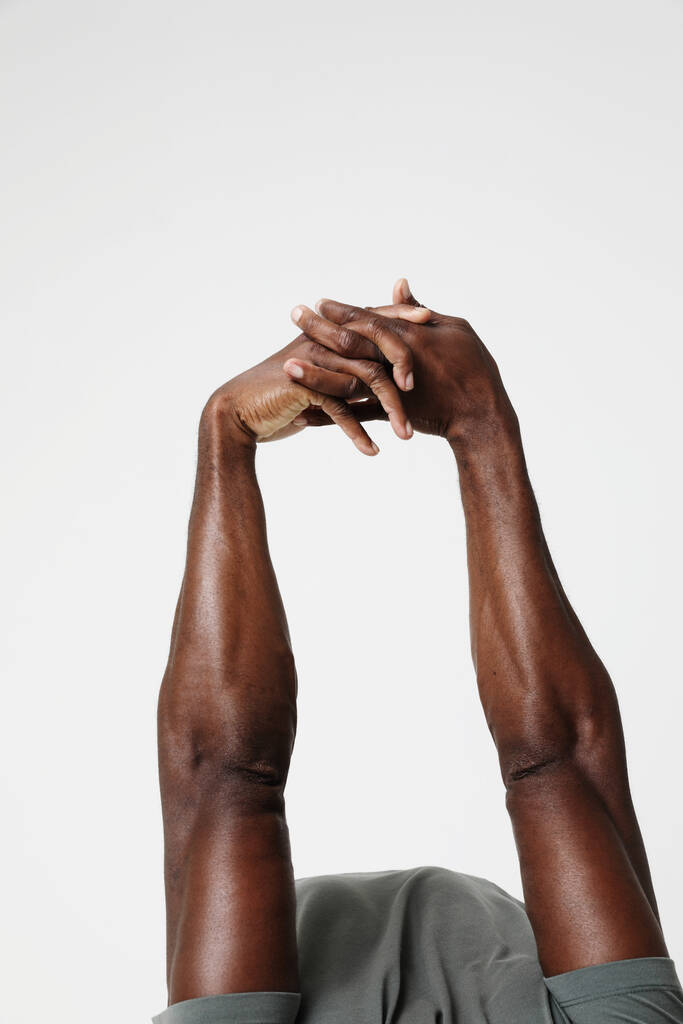 Przycięte zdjęcie wysportowanego czarnego mężczyzny wykonującego ćwiczenia rozciągające mięśnie. Pionowe. Wysokiej jakości zdjęcie. - Zdjęcie, obraz