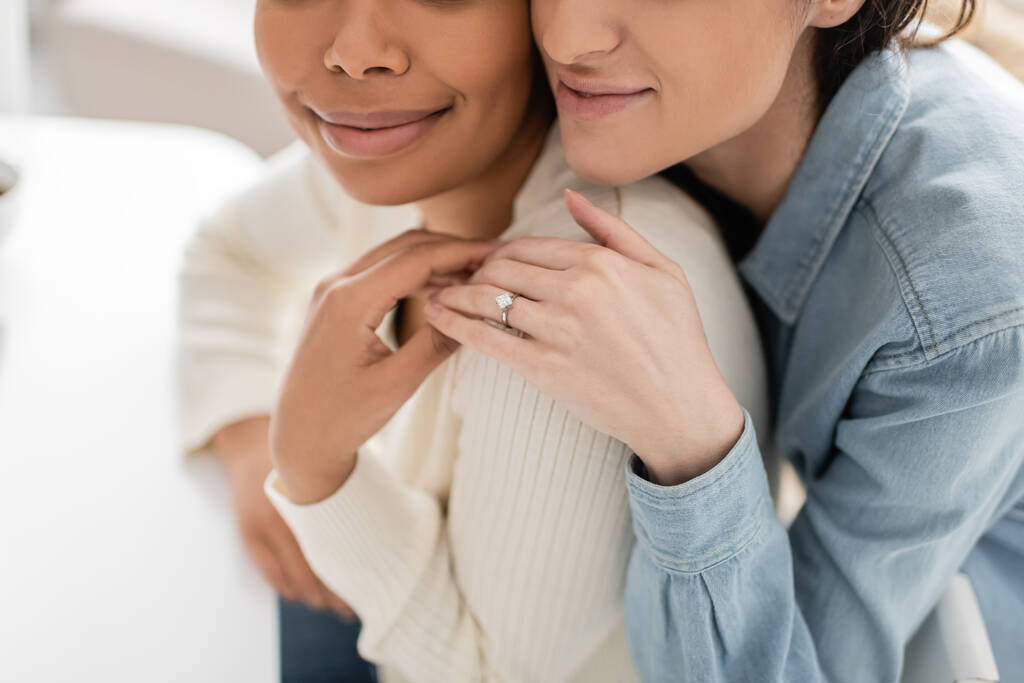 částečný pohled na angažované multiiraciální lesbické ženy se zásnubním prstenem objímající se navzájem  - Fotografie, Obrázek